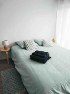 Una cama con dos almohadas y una bolsa. en Studio dans impasse proche plages Hossegor, en Bénesse-Maremne