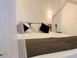 1 dormitorio con 1 cama con almohadas blancas y negras en Milla villa, en Hikkaduwa