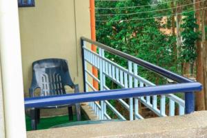 EuphGlory Accomodations في Kakamega: مقعد أزرق على شرفة مع كرسي