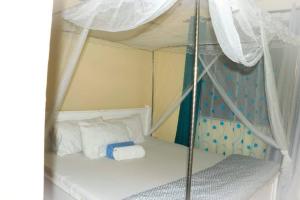 EuphGlory Accomodations في Kakamega: غرفة نوم مع سرير المظلة مع الوسائد البيضاء