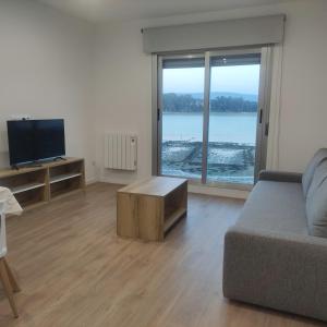 a living room with a couch and a flat screen tv at Apartamentos O Grove Awa Bay in O Grove