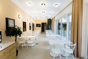 a restaurant with white tables and white chairs at Artist hotel in Subotica