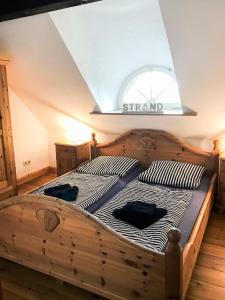 ein Holzbett in einem Zimmer mit Fenster in der Unterkunft Haubarg am Meer in Vollerwiek