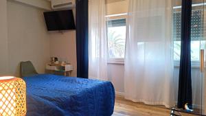 sypialnia z niebieskim łóżkiem i oknem w obiekcie Baia di Luna w mieście Santa Marinella
