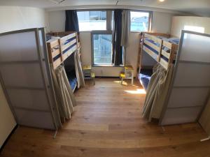 a room with bunk beds and a wooden floor at Guest House Matsu in Osaka