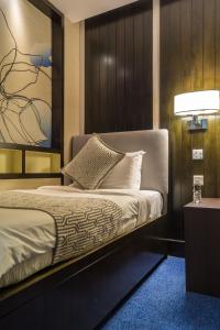 um quarto com uma cama com uma cabeceira e um candeeiro em Ambassador Transit Lounge Terminal 3 em Singapura