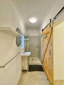 a bathroom with a sink and a wooden door at Living The Breede-Lorigan House in Malgas