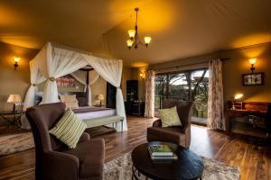 a bedroom with a bed and a living room at Lions Paw Ngorongoro in Ngorongoro