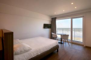 una camera da letto con un letto e un tavolo e una grande finestra di Hotel Sandeshoved Zeedijk a Nieuwpoort