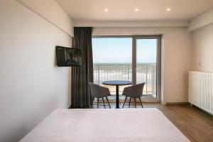 een slaapkamer met een bed en een tafel en stoelen bij Hotel Sandeshoved Zeedijk in Nieuwpoort