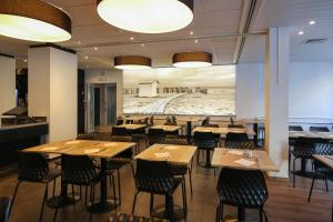 un ristorante con tavoli e sedie in legno e un murale di Hotel Sandeshoved Zeedijk a Nieuwpoort