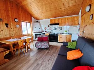 ein Wohnzimmer mit einem Sofa und einem Tisch sowie eine Küche in der Unterkunft Maison Elios 2 CIR-TORGNON-0005 in Torgnon