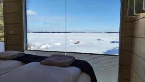 um quarto com uma janela com vista para um campo coberto de neve em Loma Luonnonlapsi Tuli-mökki em Sotkamo
