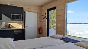 um quarto com uma cama e uma grande janela em Loma Luonnonlapsi Tuli-mökki em Sotkamo