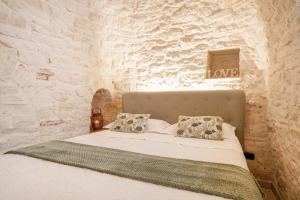 ein Schlafzimmer mit einem Bett in einer Steinmauer in der Unterkunft Trulli di Zia Vittoria in Alberobello