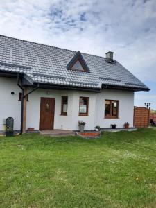 ein weißes Haus mit grünem Rasen davor in der Unterkunft Pensjonat Wiktoria Mielenko in Mielenko