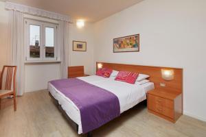 a bedroom with a large bed and a window at Hotel Centrale in Nago-Torbole