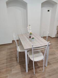 La Prima Dimora Luxury Home في Grumo Appula: طاولة طعام مع كراسي بيضاء وورود عليها