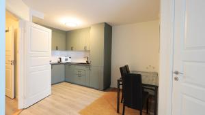 a kitchen with green cabinets and a table and chairs at Apartment with two bedrooms and parking in Stavanger