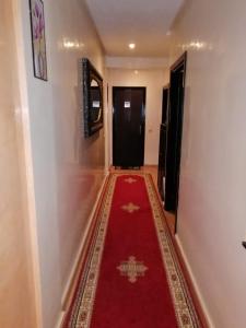 einen Flur mit rotem Teppich und schwarzer Tür in der Unterkunft Mohammed V Airport Appartment in Deroua