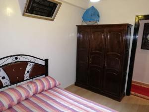 a bedroom with a bed and a wooden cabinet at Mohammed V Airport Appartment in Deroua