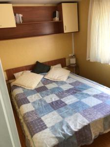 - une chambre avec un lit et une couette en damier dans l'établissement Mobil home Aluna Vacances camping Sunêlia, à Ruoms