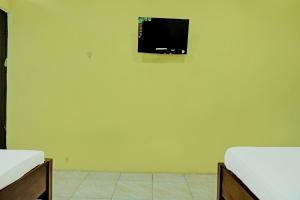 Habitación con 2 camas y TV en la pared. en Capital O 92316 Wisma Widya Loka Pratama, 