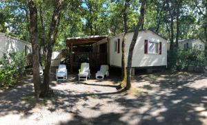 un terrain de camping avec des chaises, une maison et des arbres dans l'établissement Mobil home Aluna Vacances camping Sunêlia, à Ruoms