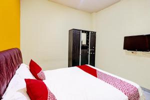 a bedroom with a bed with red pillows and a television at OYO 92322 Hasan House Syariah in Nagoya