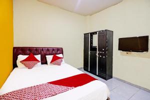 1 dormitorio con 1 cama con almohadas rojas y TV en OYO 92322 Hasan House Syariah en Nagoya