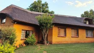 a yellow house with a thatched roof at Cozy cottage in the Cradle of Humankind in Muldersdrift