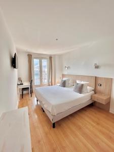 a white bedroom with a large bed and a desk at Hôtel Les Deux Coteaux in Tain-lʼHermitage