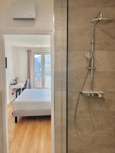 een badkamer met een douche en een bed in een kamer bij Hôtel Les Deux Coteaux in Tain-lʼHermitage