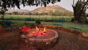 a fire pit with chairs and chairs around it at Cozy cottage in the Cradle of Humankind in Muldersdrift