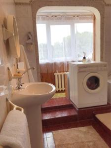 a bathroom with a sink and a washing machine at Erdvus butas su balkonu šalia ežero ir stadiono in Visaginas