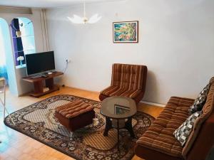 a living room with a couch and chairs and a table at Erdvus butas su balkonu šalia ežero ir stadiono in Visaginas