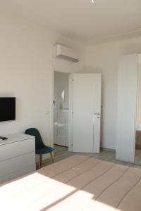 Cette chambre blanche comprend un lit et une chaise. dans l'établissement Da Mariella case vacanza - Bilocale Sunset vista mare, à Sanremo