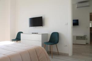 - une chambre avec 2 chaises et une télévision murale dans l'établissement Da Mariella case vacanza - Bilocale Sunset vista mare, à Sanremo