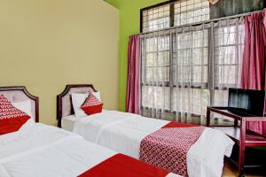 1 dormitorio con 2 camas y ventana en OYO 92331 Rindu Sempadan Cottage, en Pekanbaru