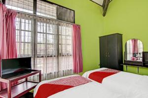 - 2 lits dans une chambre dotée de murs verts et de fenêtres dans l'établissement OYO 92331 Rindu Sempadan Cottage, à Pekanbaru