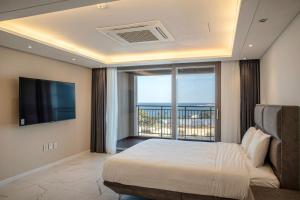 a bedroom with a large bed and a large window at Villa de Aewol in Jeju