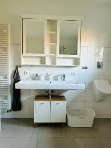 ein weißes Badezimmer mit einem Waschbecken und einem Spiegel in der Unterkunft Die Ibbenbürener Ferienstube in Ibbenbüren