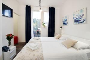 a white bedroom with two beds and a window at Art Like Rooms in Zagreb