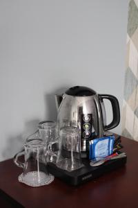 a coffee pot and glasses on a tray on a table at Hôtel Crocus Caen Mémorial in Caen