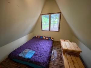 a small bedroom with a purple bed and a wooden table at Red orchid pai Thailand in Pai