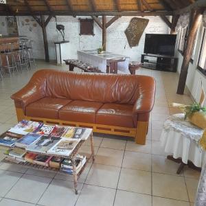 a brown leather couch in a living room with a table at Ombo Rest Camp in Okahandja
