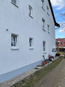 biały budynek z oknami i roślinami na boku w obiekcie Wohnung für Monteure in Unterallgäu 