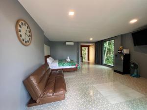 a living room with a couch and a clock on the wall at Ton Pling Khao Lak Villa in Khao Lak