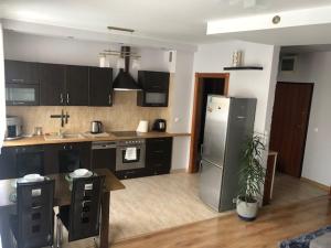 cocina con armarios negros y nevera de acero inoxidable en Apartamenty Modrzewiowa, en Suwałki