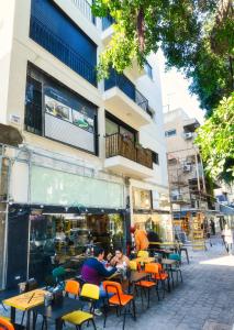 um grupo de pessoas sentadas em mesas em frente a um edifício em Near the beach & modern em Tel Aviv